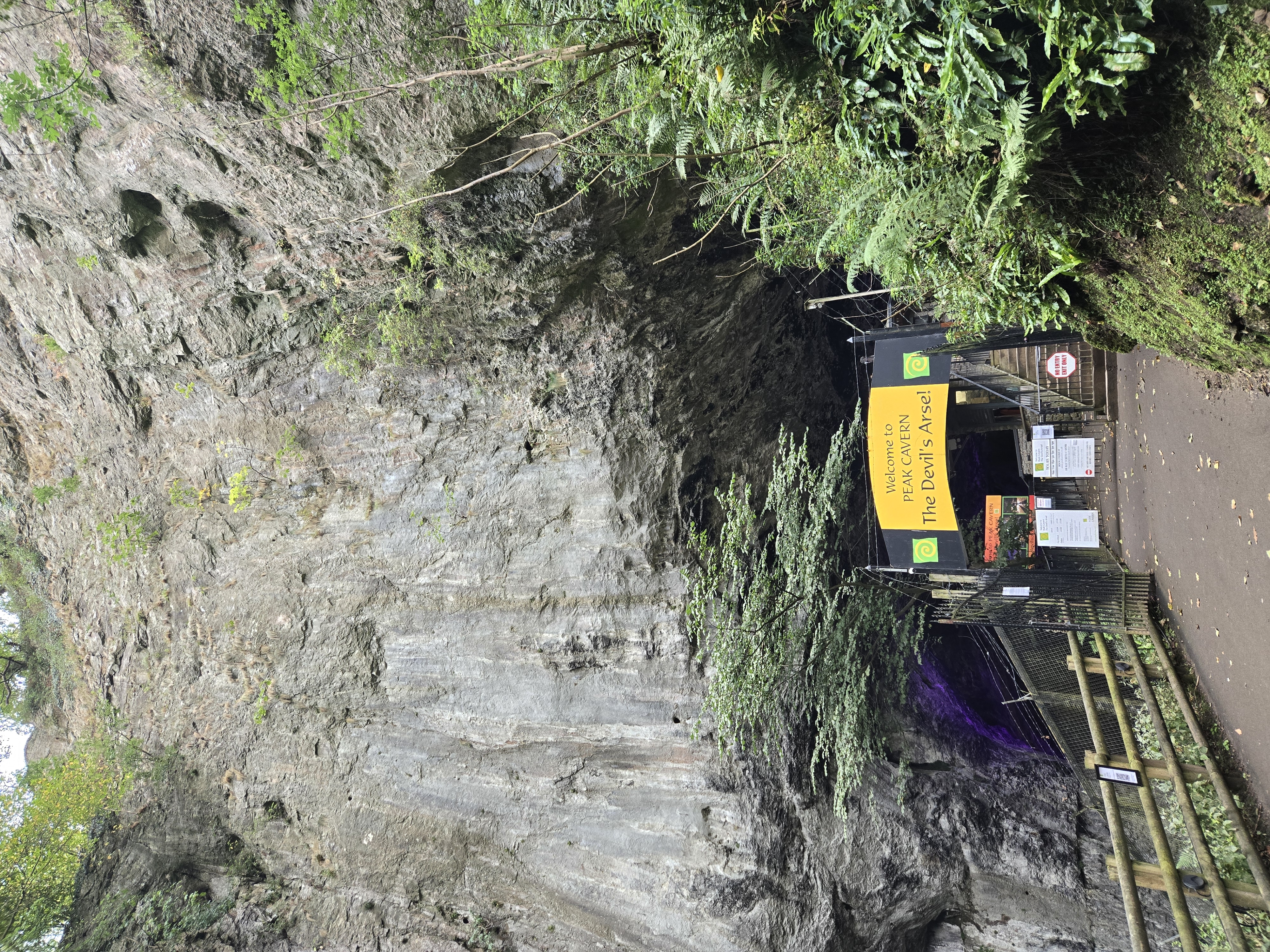 Cave entrance at foot of high limestone cliff