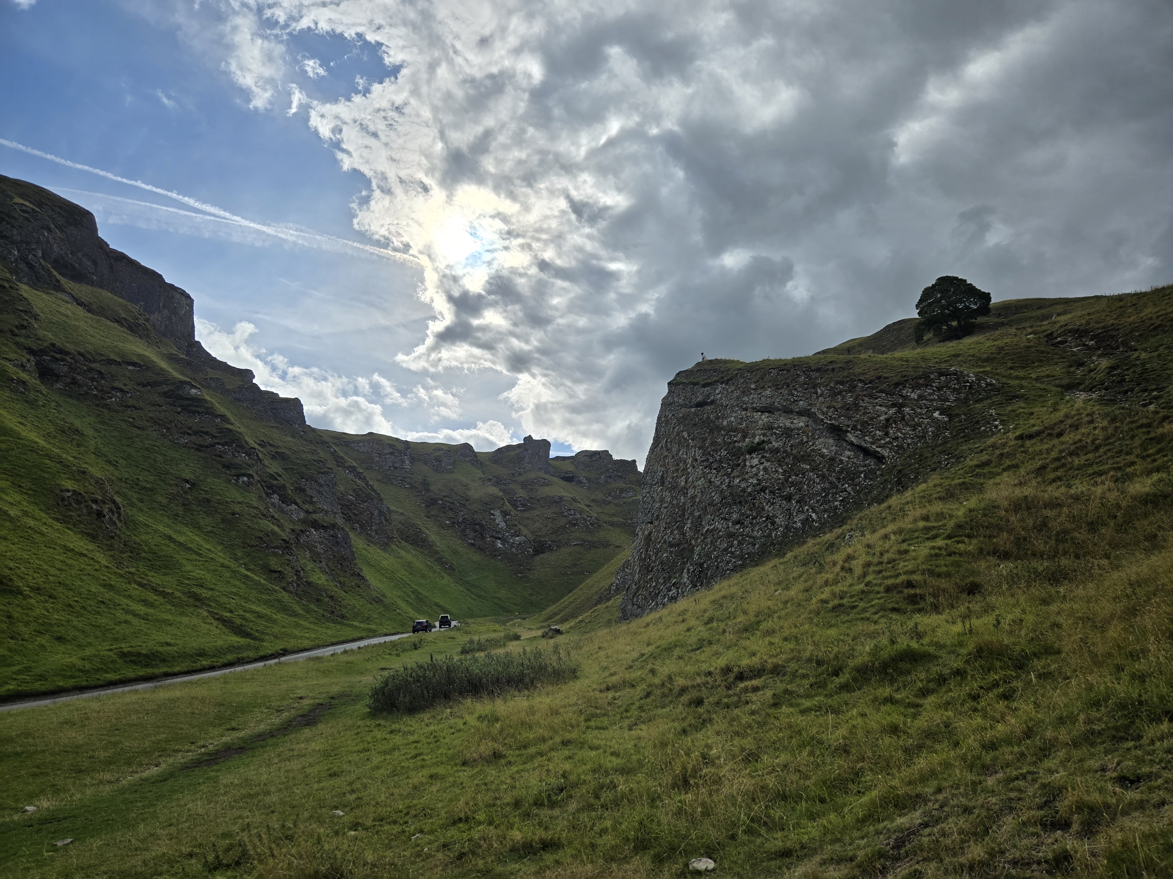 Deep limestone gorge with cars on road in distance
